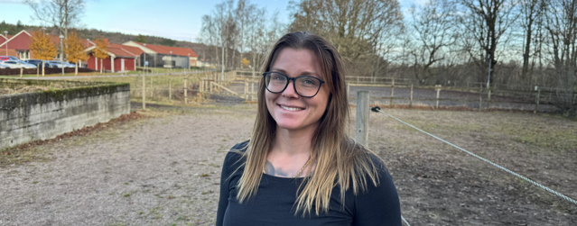 Bild på behandlingssamordnare Ida som står i en hästhage.